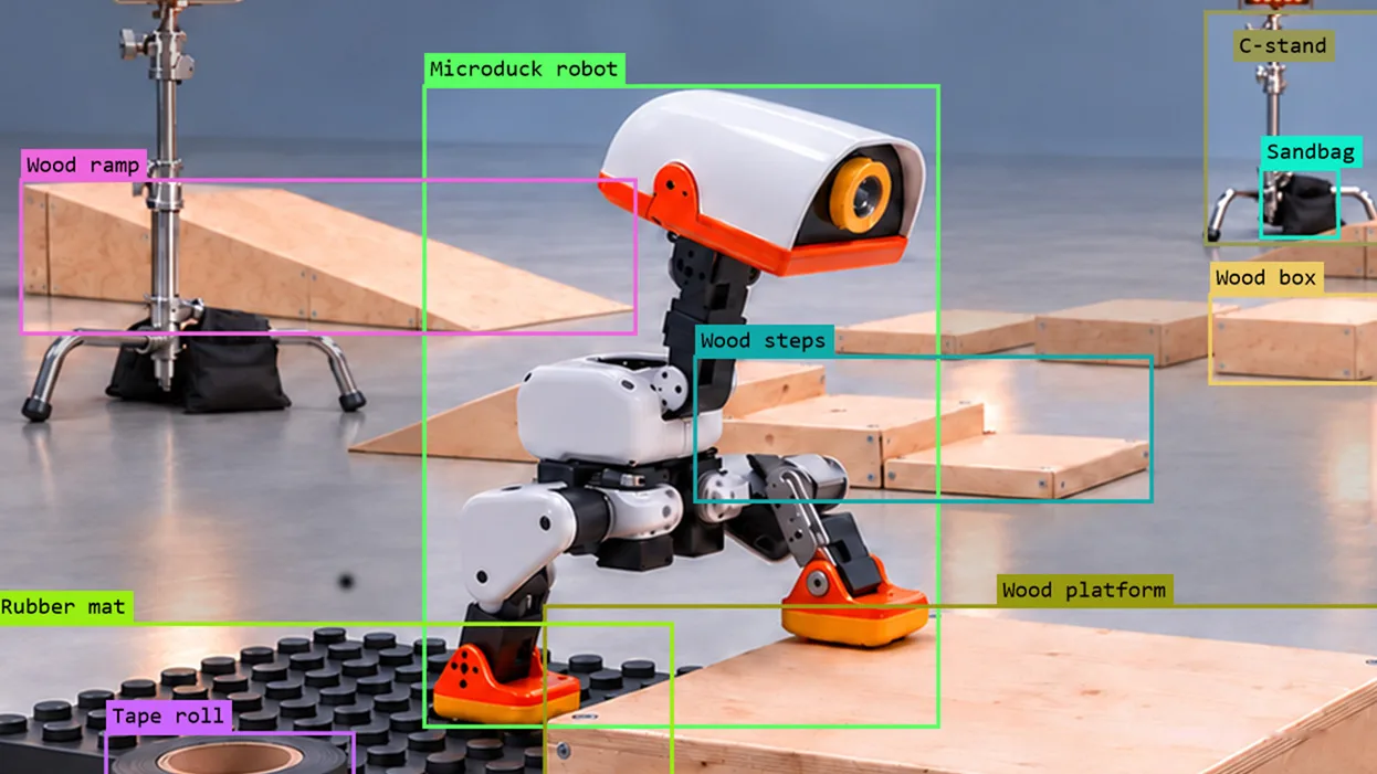 Microduck robot in an obstacle course with labeled ramps, platforms, a rubber mat, and other objects.