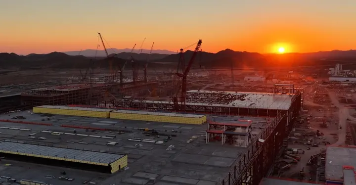 A desert sunset on the horizon behind a data center under construction.
